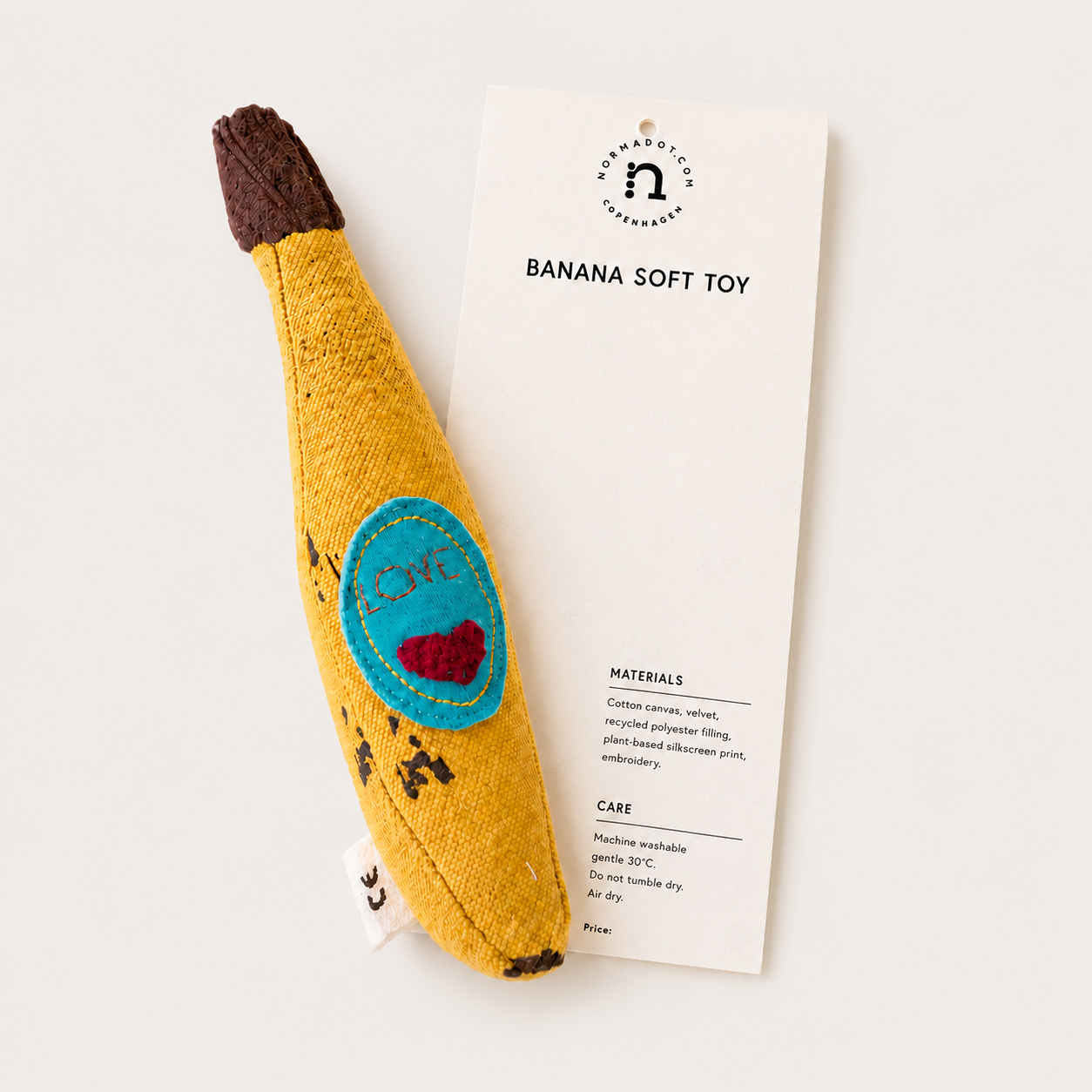 Handmade banana soft toy with product tag on a light studio background.