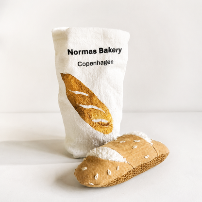 
Handmade fabric baguette with a printed cotton bakery bag on a light studio background.


