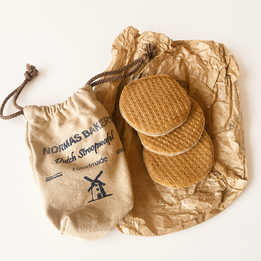 Three handmade Dutch stroopwafel play food pieces with printed cotton storage bag on crumpled kraft paper.