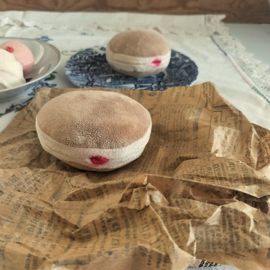 Handmade fabric Berliner with a red jam detail on vintage paper, with more play food and embroidered lace in the background.