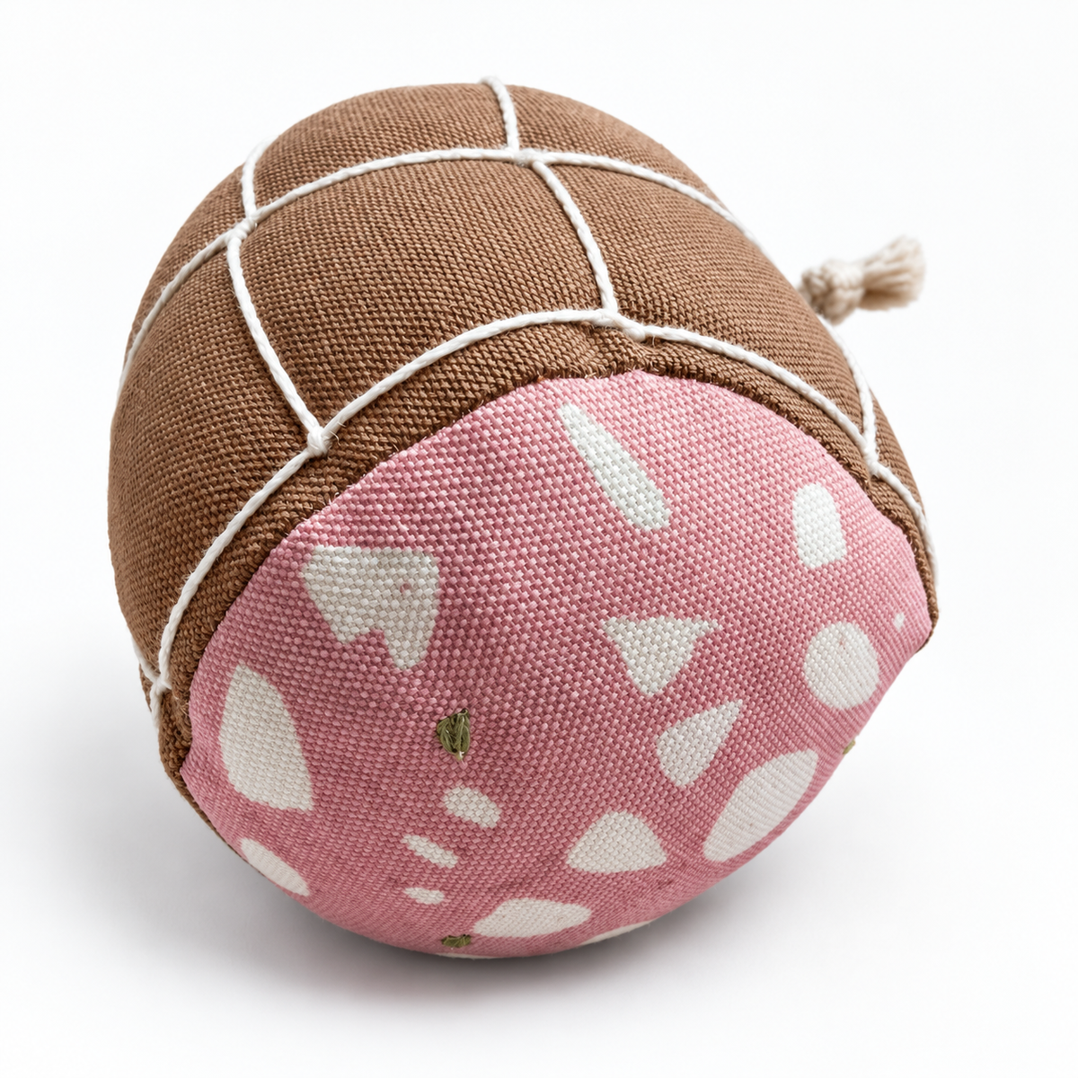 Front view of handmade fabric mortadella play food, featuring a pink patterned end, brown cotton canvas and white string netting on a soft off-white studio background.