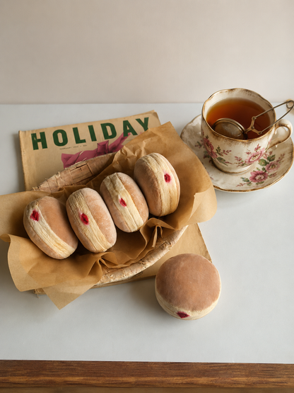 Handmade Berliner Pfannkuchen play food toys with raspberry jam details displayed in a woven basket beside a floral teacup