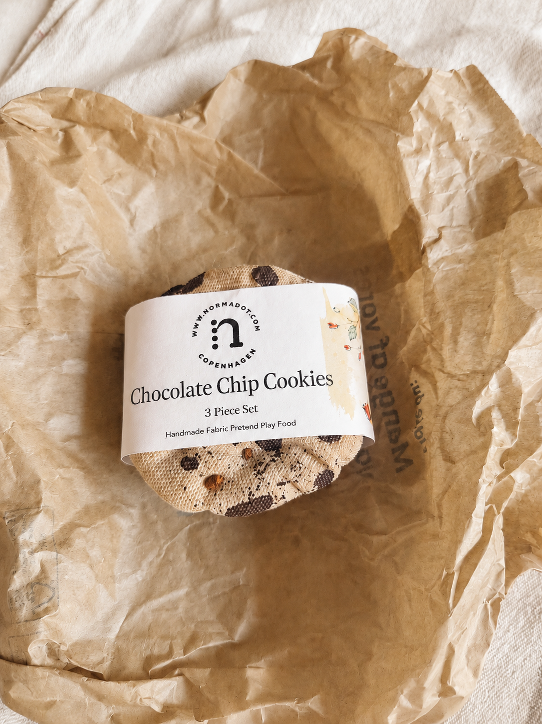 Three handmade fabric chocolate chip cookies wrapped with a normadot product label.