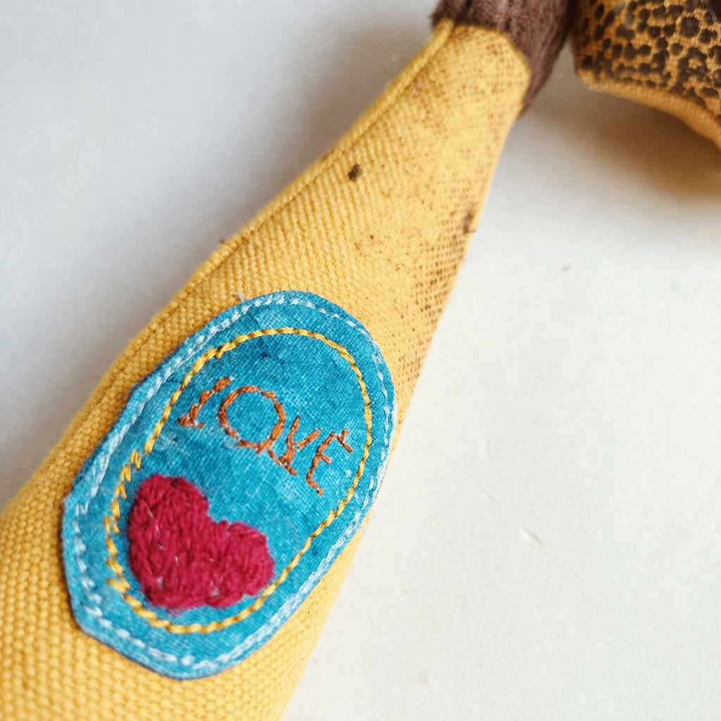 Yellow fabric toy banana with a 'LOVE' patch featuring a red heart on a white background