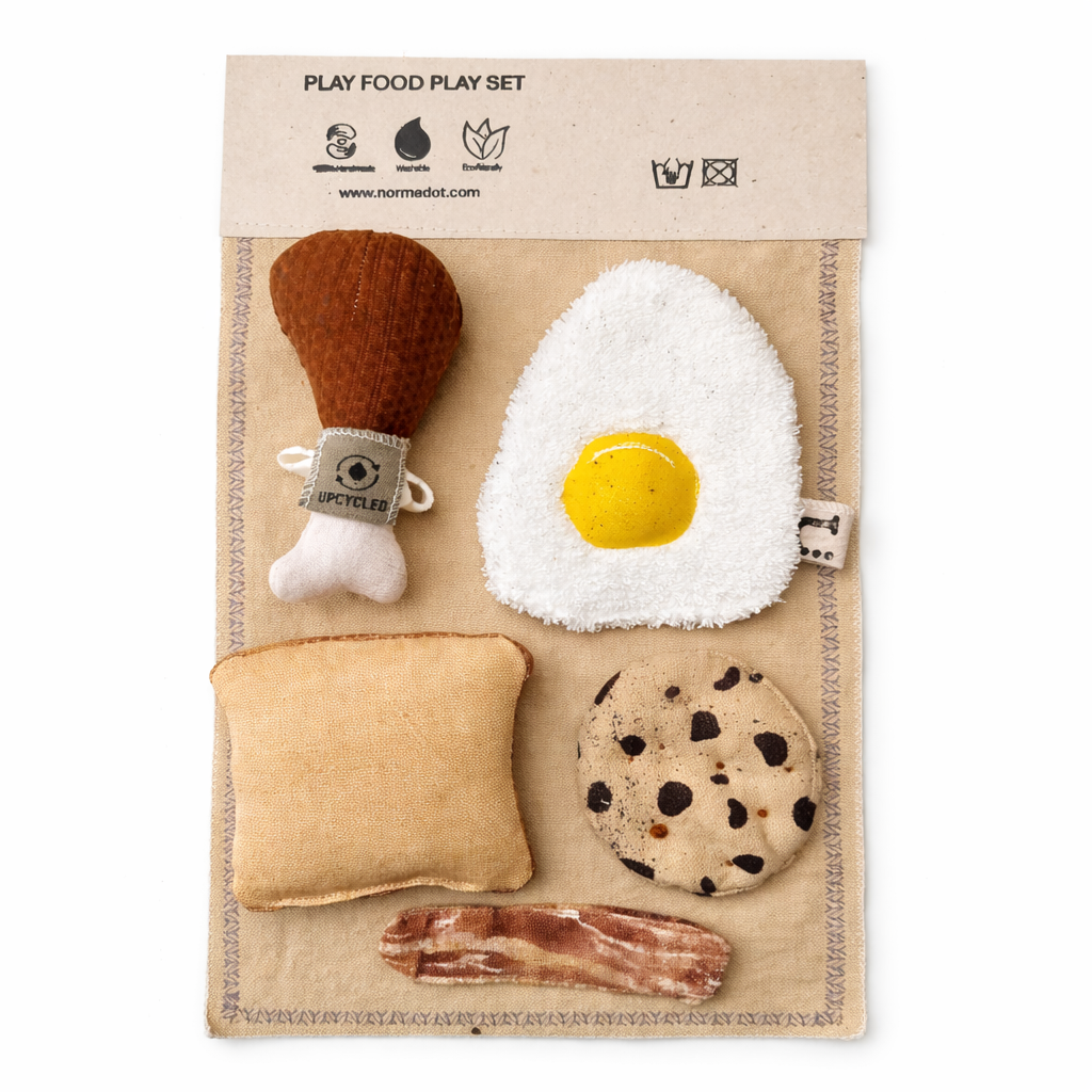 Handmade fabric play food set with egg, drumstick, toast, cookie and bacon on a cotton play mat