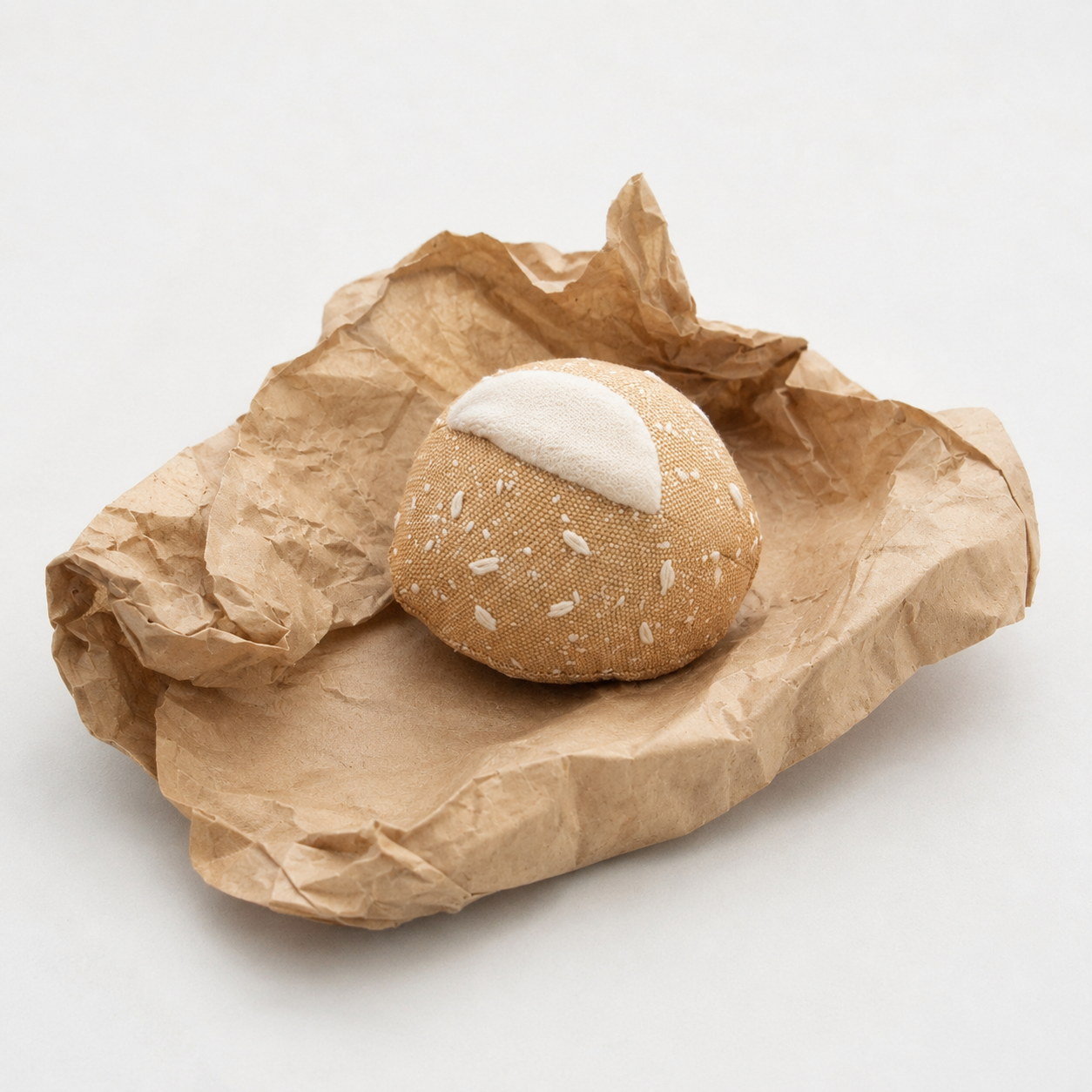 Handmade fabric bread roll play food displayed on crumpled brown bakery paper, made in Denmark by normadot